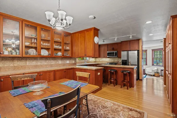 a kitchen with a refrigerator a stove a sink and a dining table with wooden floor