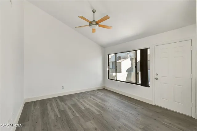 an empty room with wooden floor a ceiling fan and windows