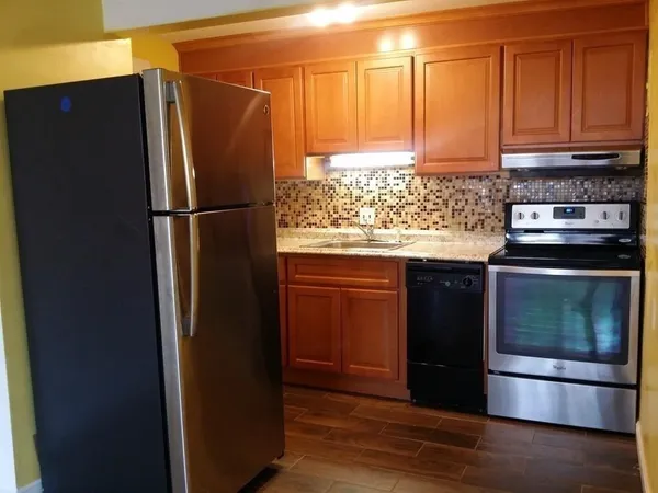 a kitchen with granite countertop wood cabinets and stainless steel appliances
