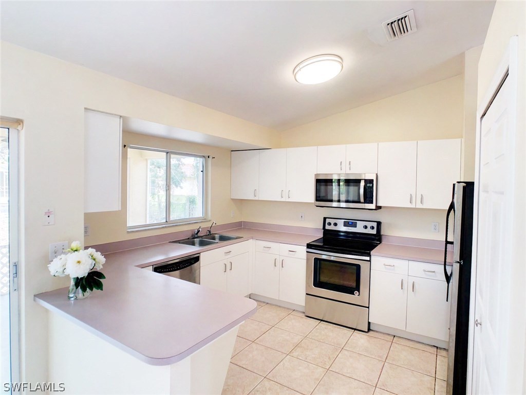 17424 Delaware Road Fort Myers, FL 33967 - Photo 5 of 12 a kitchen with stainless steel appliances granite countertop a sink a stove a microwave a refrigerator a counter space and cabinets