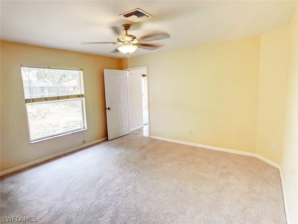 17424 Delaware Road Fort Myers, FL 33967 - Photo 7 of 12 en empty room with windows and chandelier fan
