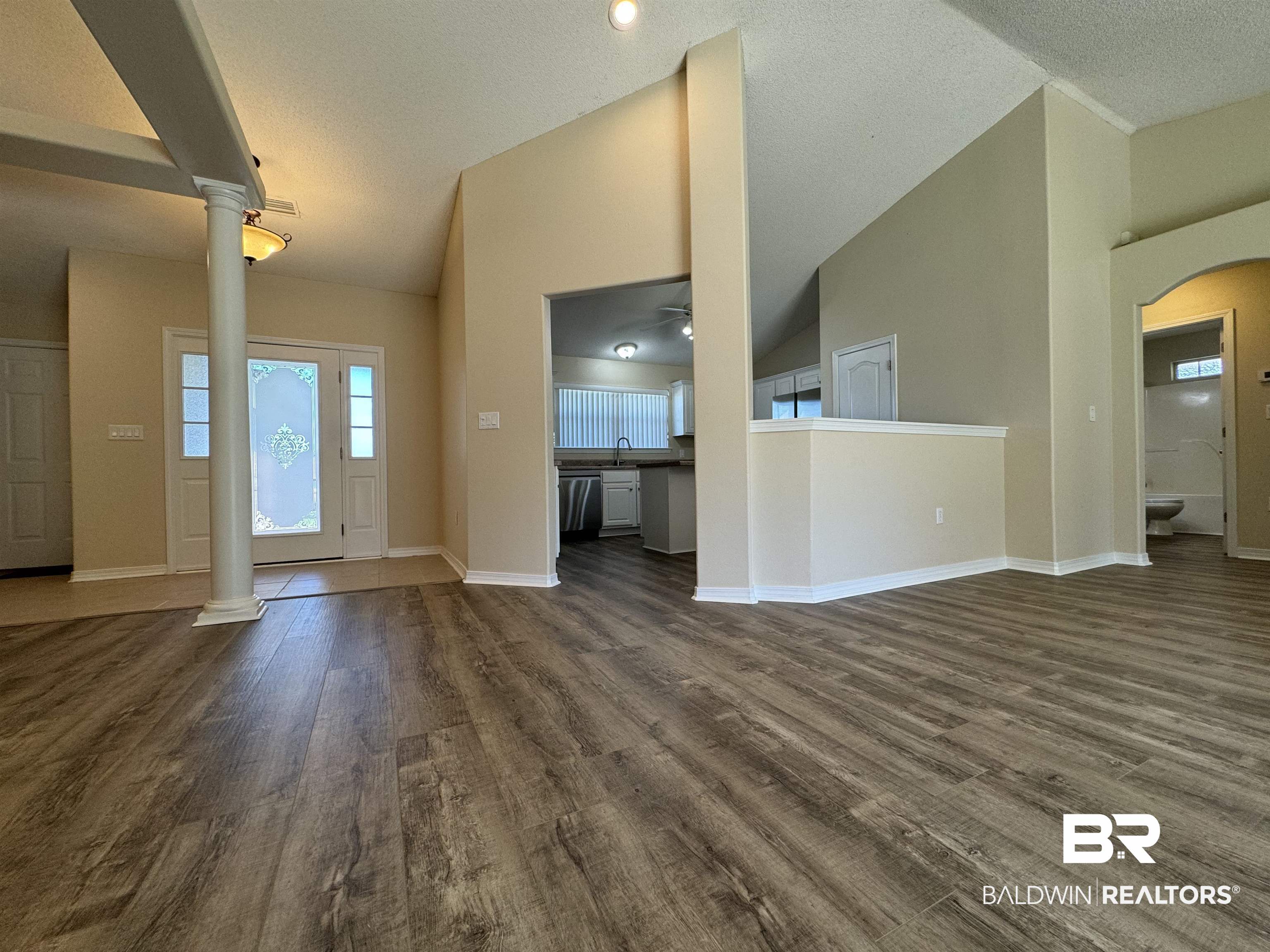 32769 Arbor Ridge Circle Lillian, AL 36549 - Photo 5 of 36 Unfurnished living room with ornate columns, dark hardwood / wood-style floors, high vaulted ceiling, and a textured ceiling