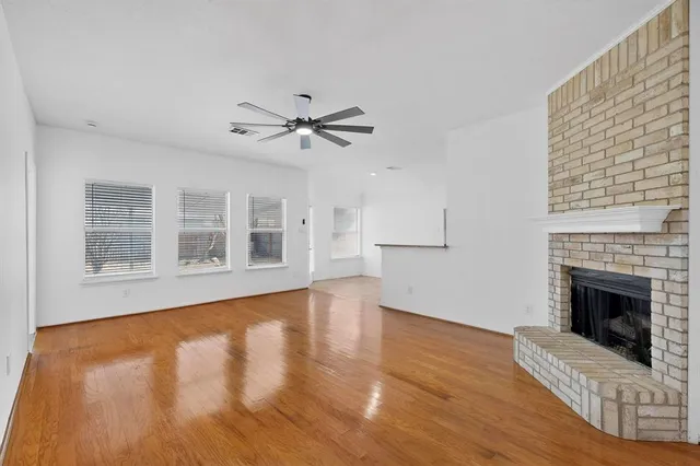 a view of an empty room with wooden floor and a fireplace
