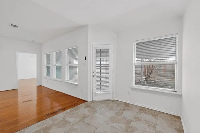 a view of an empty room with wooden floor and windows