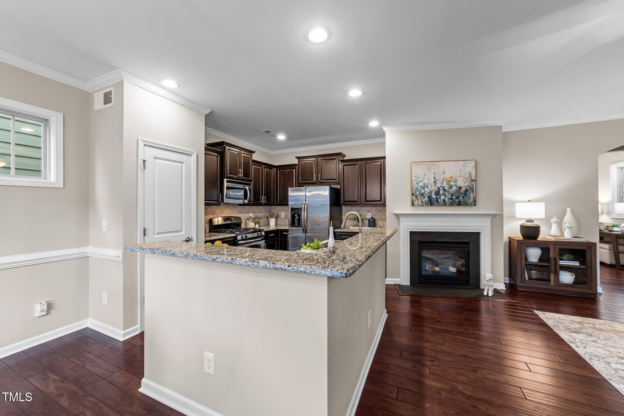5644 Wade Park Boulevard Raleigh, NC 27607 - Photo 8 of 29 a kitchen with stainless steel appliances granite countertop a refrigerator oven a sink dishwasher and a fireplace with wooden floor