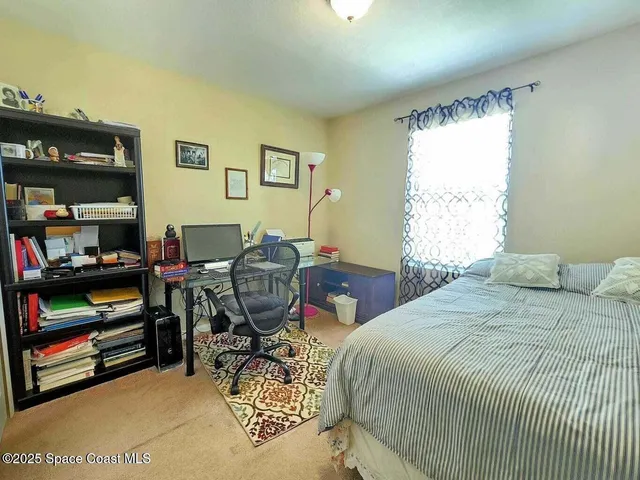 a bedroom with a bed a dresser and a large window