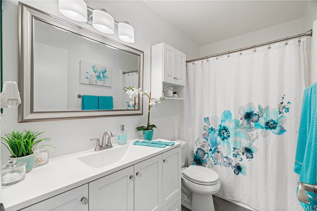 1040 West MacArthur Boulevard, Unit 104 Santa Ana, CA 92707 - Photo 13 of 30 a bathroom with a sink a mirror a flower and a window