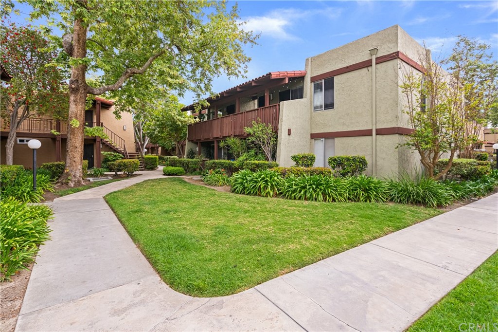 1040 West MacArthur Boulevard, Unit 104 Santa Ana, CA 92707 - Photo 28 of 30 a view of a white house with a small yard plants and a large tree