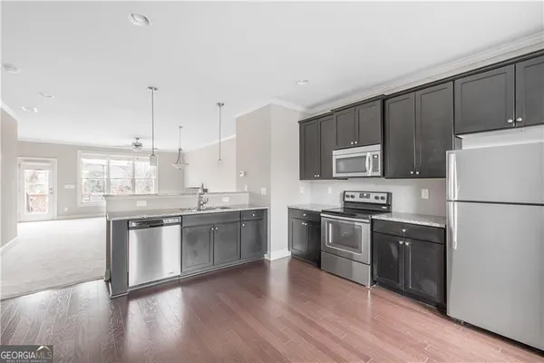 a kitchen with stainless steel appliances granite countertop wooden floors and white cabinets