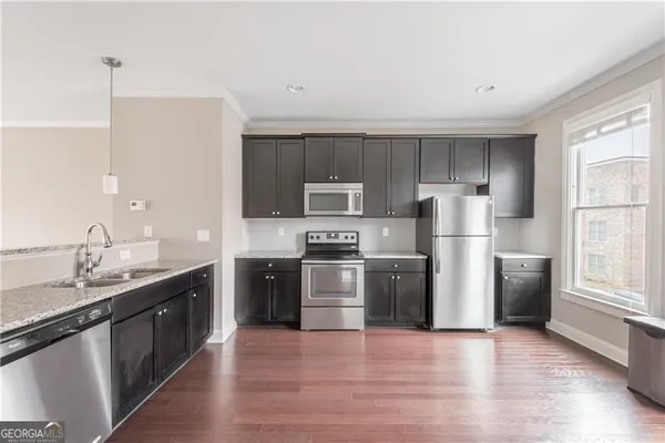 a kitchen with stainless steel appliances granite countertop a refrigerator a stove top oven a sink and dishwasher with wooden floor