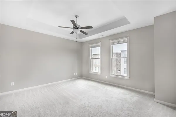 an empty room with chandelier fan and windows