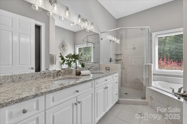 a bathroom with a granite countertop sink a mirror a vanity and a bathtub