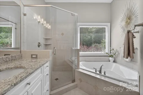 a bathroom with a granite countertop tub a sink and a window