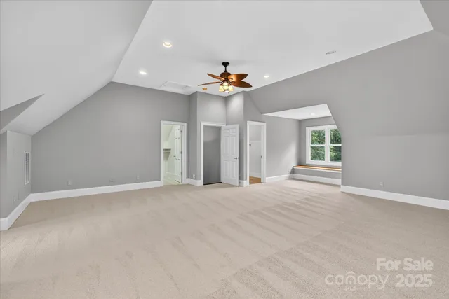 a view of an empty room with chandelier fan and window