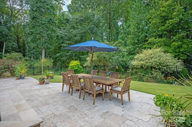 a view of a table and chairs under an umbrella in backyard