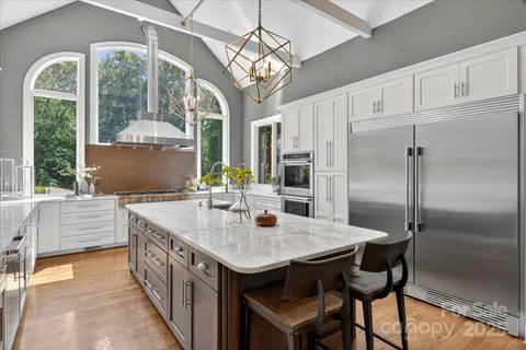 a kitchen with stainless steel appliances granite countertop a sink a refrigerator and a dining table