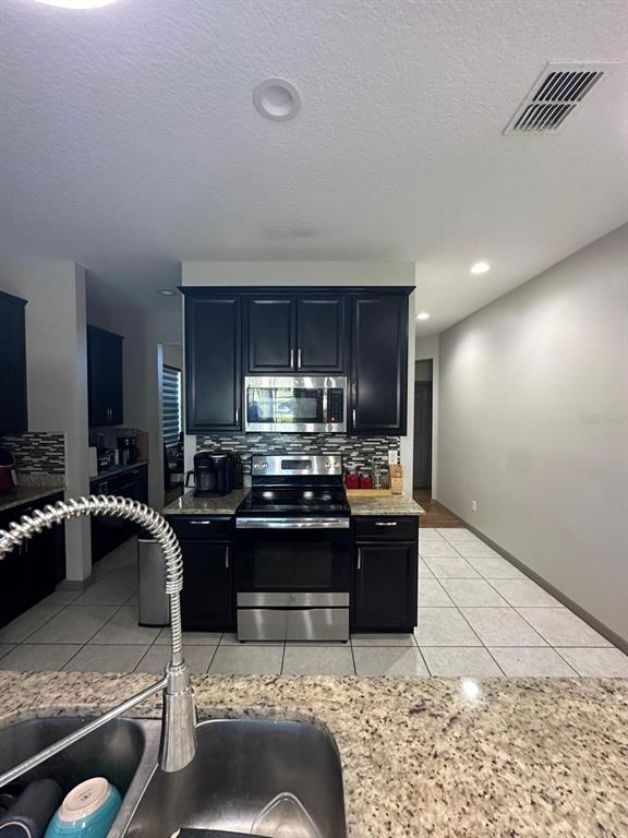 3100 Rocky River Road Kissimmee, FL 34746 - Photo 19 of 33 a kitchen with stainless steel appliances kitchen island granite countertop a refrigerator stove and sink