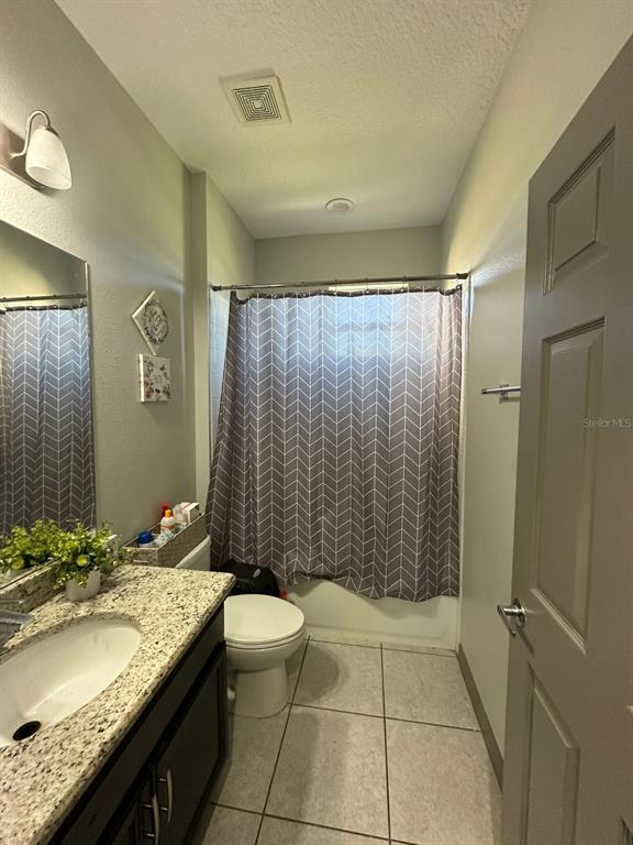 3100 Rocky River Road Kissimmee, FL 34746 - Photo 32 of 33 a bathroom with a granite countertop sink a toilet a mirror and shower