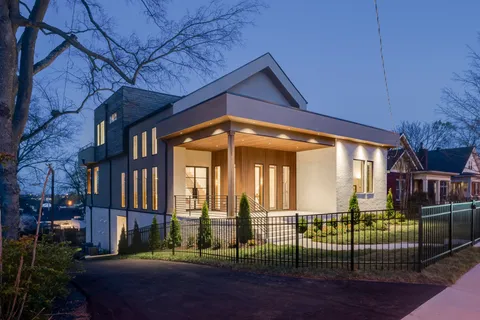 a view of a brick house with large windows and a yard