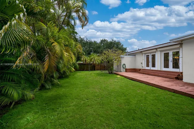a backyard of a house with plants and large trees