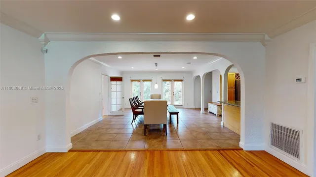 a dining room with wooden floor a chandelier a glass table and chairs
