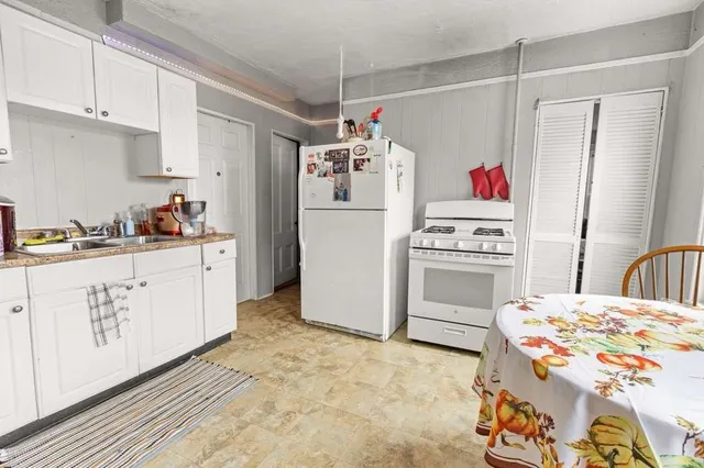 a kitchen that has a lot of white cabinets and white appliances