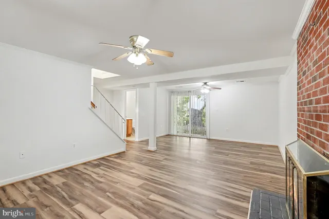 a view of an empty room with wooden floor and a chandelier fan