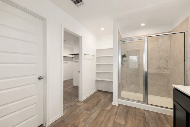 a bathroom with a walk in closet and wooden floor