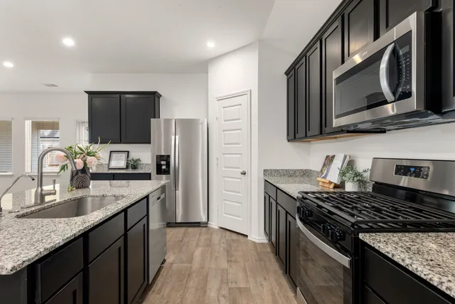 a kitchen with stainless steel appliances granite countertop a sink stove microwave and refrigerator
