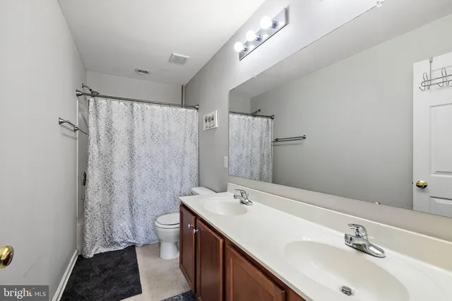 a bathroom with a sink a toilet a mirror and shower curtain