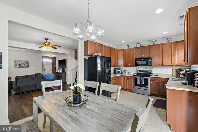 a kitchen with stainless steel appliances granite countertop a refrigerator a stove a sink dishwasher a dining table and chairs with wooden floor
