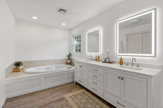 a bathroom with a tub a sink and mirror