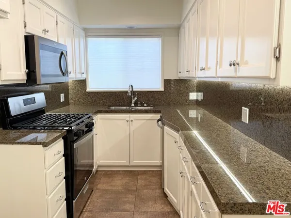 a kitchen with stainless steel appliances granite countertop a stove a sink and a microwave