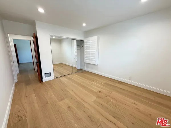 an empty room with wooden floor and mirror