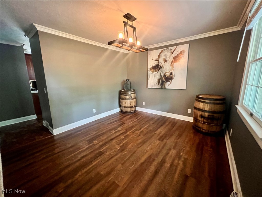 3840 Tabor Ridge Road Northeast Mineral City, OH 44656 - Photo 20 of 40 Unfurnished dining area featuring dark wood-type flooring, crown molding, and a chandelier