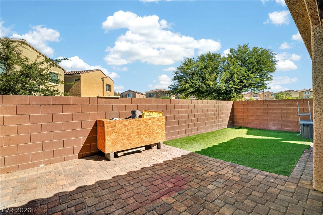 6281 Angora Peak Lane Las Vegas, NV 89115 - Photo 32 of 34 A well-maintained yard features a brick patio and a green lawn, perfect for outdoor relaxation.