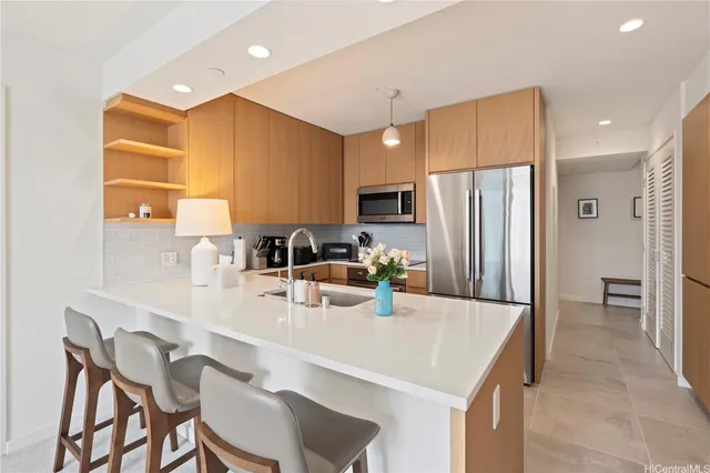 a kitchen with a refrigerator a stove a sink and a dining table with wooden cabinet