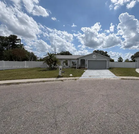 a front view of a house with a yard and a large tree