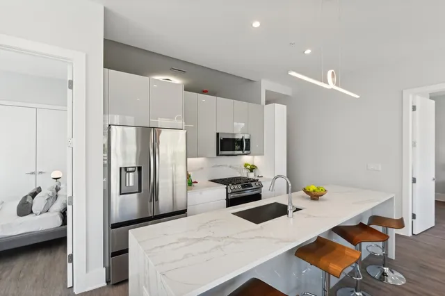 a kitchen with stainless steel appliances kitchen island granite countertop a refrigerator a stove and a sink with wooden floor