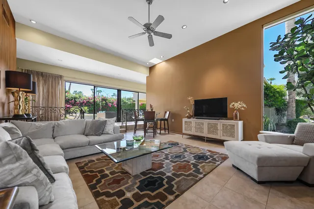 a living room with furniture a flat screen tv and a large window