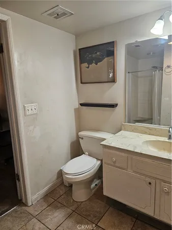 a bathroom with a granite countertop toilet sink and mirror