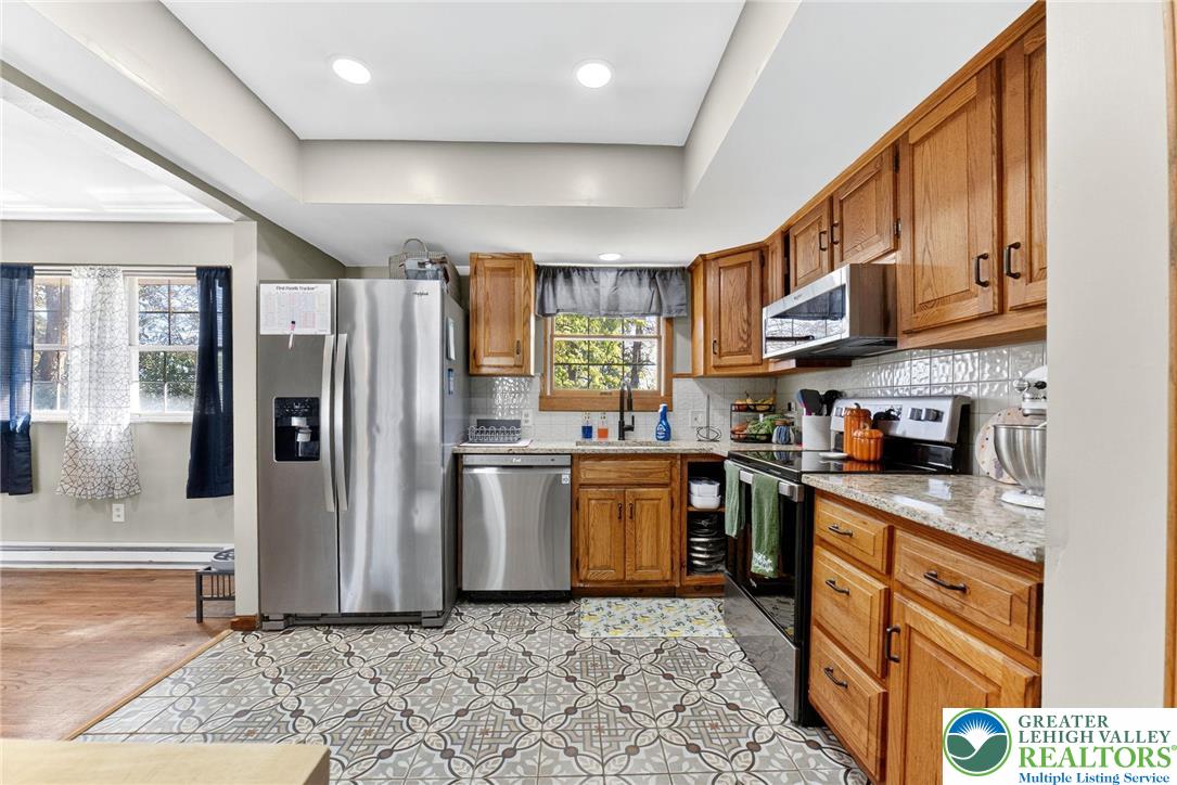 394 Manor Drive Nazareth, PA 18064 - Photo 14 of 44 a kitchen with stainless steel appliances granite countertop a refrigerator a stove and a sink with wooden cabinets
