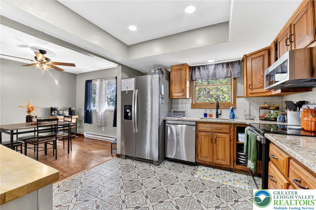 394 Manor Drive Nazareth, PA 18064 - Photo 15 of 44 a kitchen with stainless steel appliances granite countertop a stove top oven a refrigerator a sink dishwasher and a dining table with wooden floor