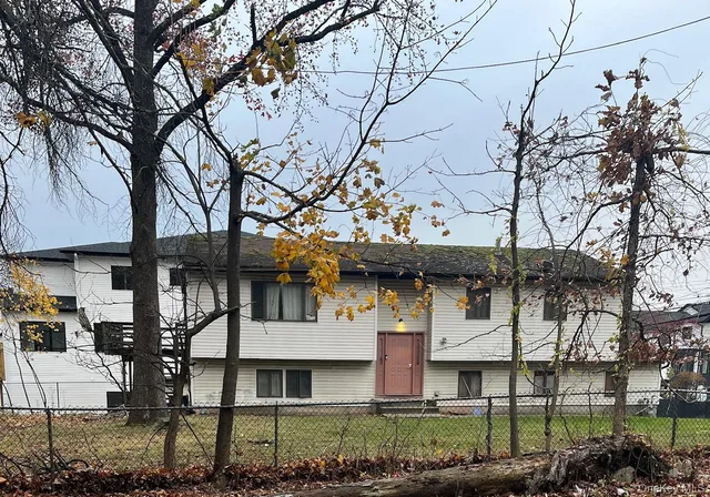 a view of a white house with a large tree