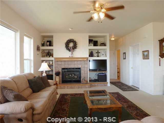 12172 Stanley Canyon Road Colorado Springs, CO 80921 - Photo 11 of 25 Main level great room with gas fireplace and panoramic windows and walkout to enjoy the breath taking views of Pikes Peak and the mountains