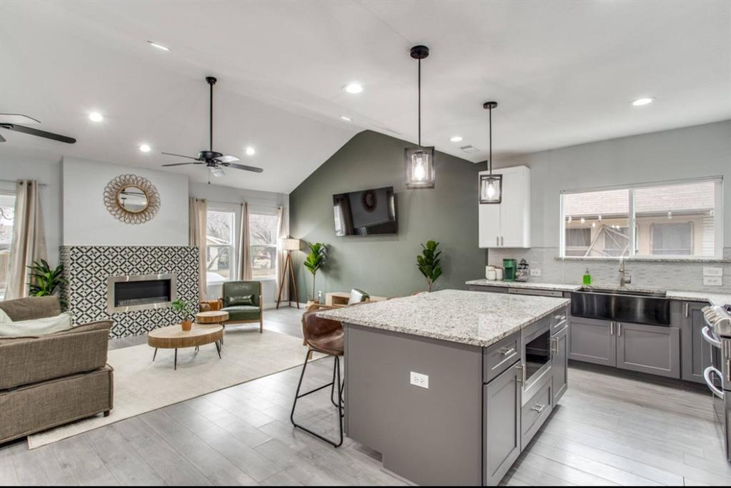 1606 West 12th Street Dallas, TX 75208 - Photo 20 of 20 Kitchen with open floor plan, light stone counters, lofted ceiling, pendant lighting, and healthy amount of natural light