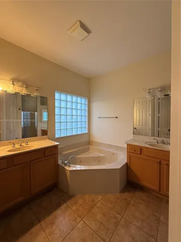 a spacious bathroom with a tub sink and mirror