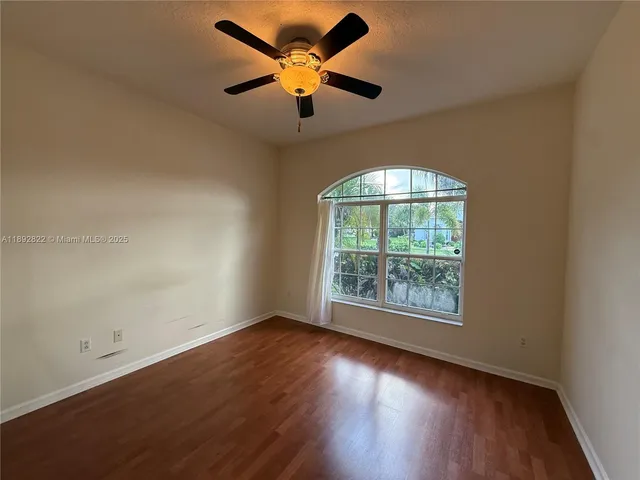an empty room with wooden floor fan and windows