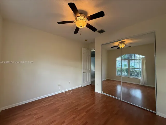 an empty room with wooden floor fan and windows