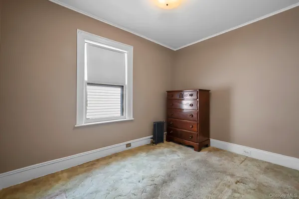 a view of an empty room with cabinet and a window
